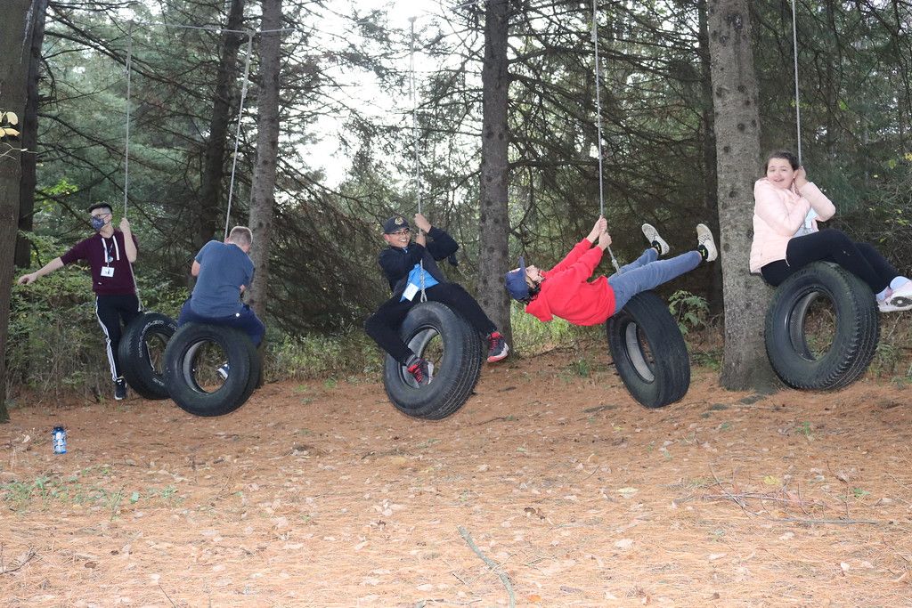 5 neurdiverse kids swing on 5 tire swings in woods